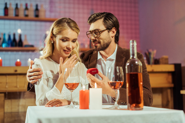 handsome man proposing to beautiful girlfriend during romantic dinner in cafe - Foto, afbeelding
