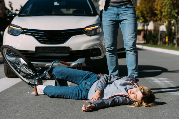 partial view of young woman mowed down by driver in car on road, car accident concept - Fotografie, Obrázek