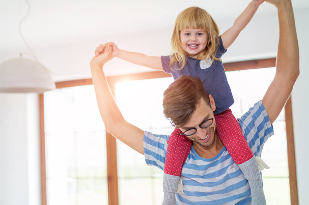 Happy father carrying daughter on shoulders at home - Photo, image
