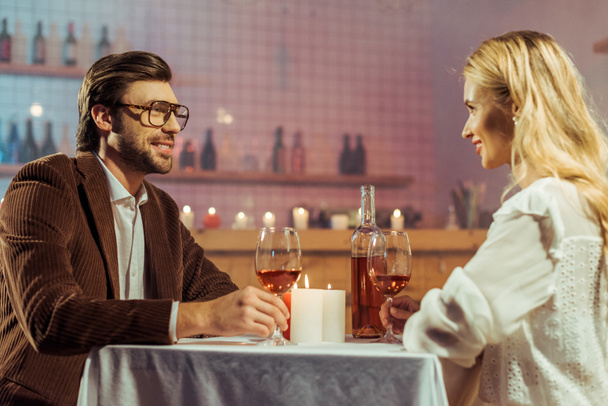 onnellinen pari juhlii pöydässä kynttilöitä ja viinilaseja ravintolassa
  - Valokuva, kuva