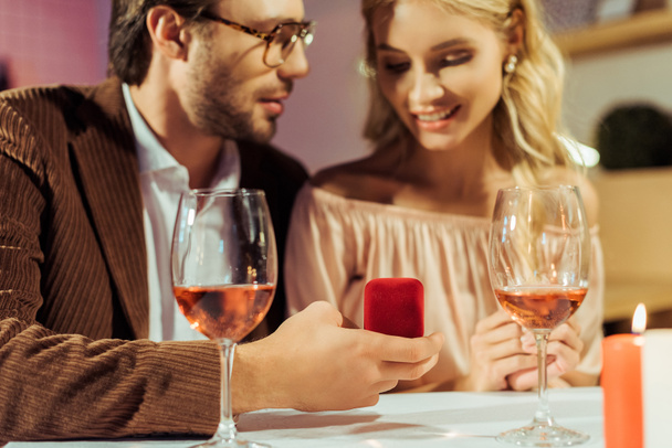 vista parziale dell'uomo che propone alla fidanzata a tavola con bicchieri di vino nel ristorante
  - Foto, immagini