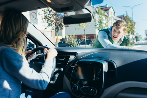 шокована жінка в машині коситься молодий чоловік на дорозі
 - Фото, зображення
