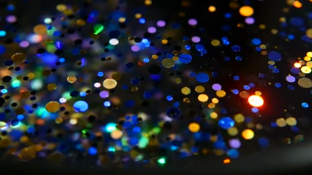 Confetti glitter multicolore sfocati e luccicanti, sfondo nero. Vacanze astratto festivo bokeh punti luce
. - Filmati, video