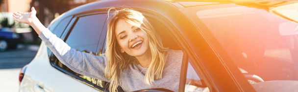muotokuva onnellinen blondi nainen vilkuttaa jollekulle ajaessaan autoa
 - Valokuva, kuva