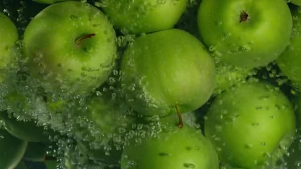 Vihreät omenat putoavat veteen mustaa taustaa vasten, super hidastettuna
 - Materiaali, video