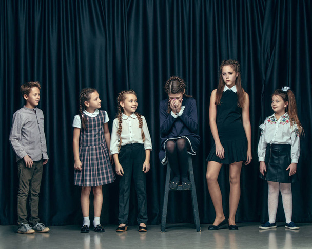 Cute stylish children on dark studio background. The beautiful teen girls and boy standing together - Foto, imagen