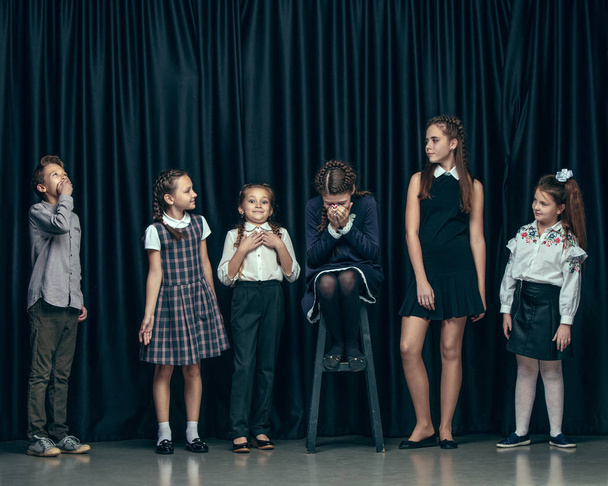 Cute stylish children on dark studio background. The beautiful teen girls and boy standing together - Valokuva, kuva