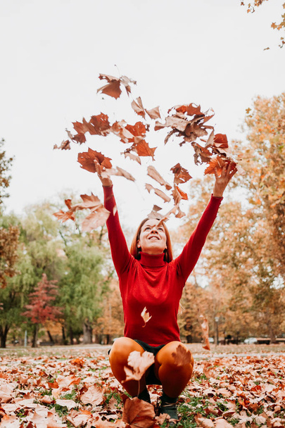Young woman throwing autumn leaves in the air in the park - Photo, Image