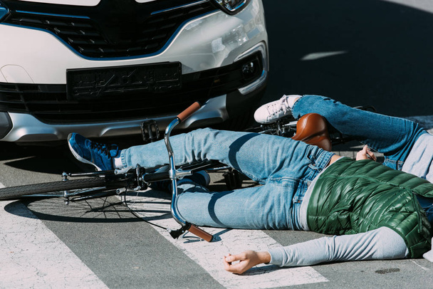 plan recadré de jeunes cyclistes allongés sur la route après une collision de la circulation
 - Photo, image