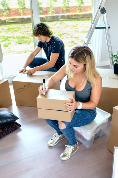 Sitting woman labeling moving boxes - Photo, Image