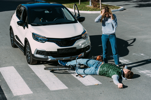 araba kazasından sonra yaralı bisikletçi duran kadın, yüksek açılı görünüş - Fotoğraf, Görsel