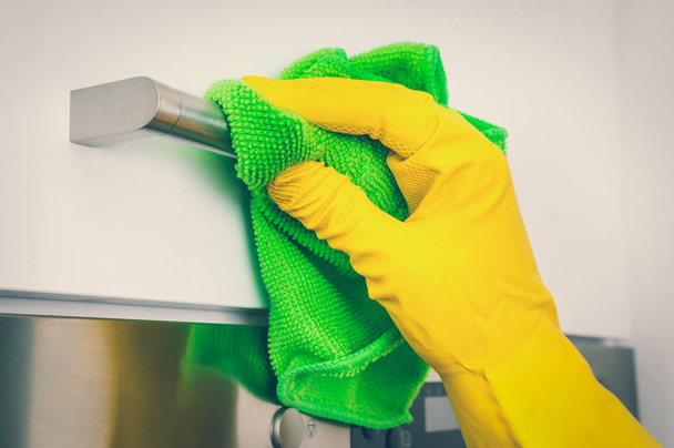 Guante de mano con trapo verde es la limpieza de asas de acero inoxidable - tareas domésticas y el concepto de limpieza - estilo retro
 - Foto, imagen