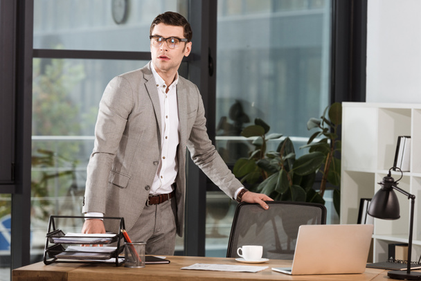 komea liikemies seisoo työpaikalla modernissa toimistossa
 - Valokuva, kuva
