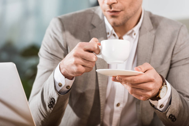 περικοπεί shot του επιχειρηματία που πίνει καφέ στο χώρο εργασίας - Φωτογραφία, εικόνα