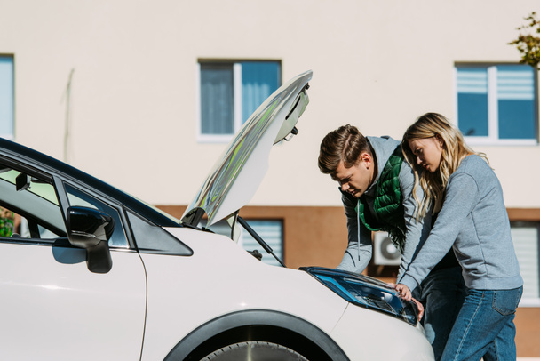 young couple repairing broken car on street  - Photo, Image