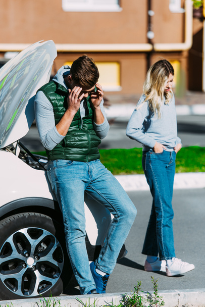 chateado jovem homem e mulher perto de carro quebrado na rua
  - Foto, Imagem