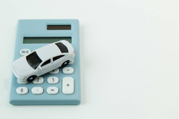 De witte auto speelgoed en blauw rekenmachine witte achtergrond - Foto, afbeelding