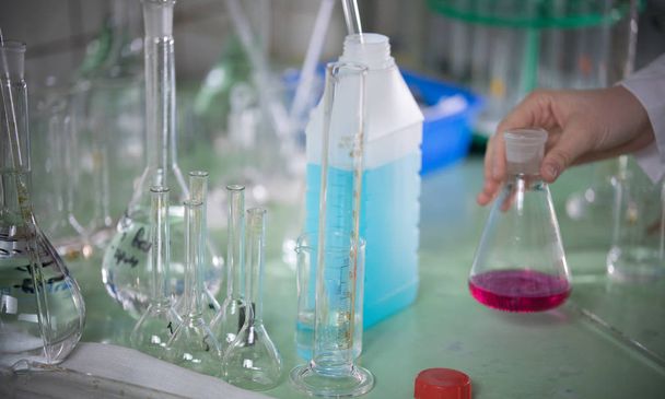 Table full of chemicals and flasks. Chemical lab. A hand touching a flask - Photo, Image