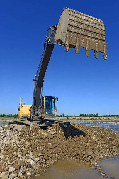 Extracción y carga de grava excavada en la corriente principal del río
 - Foto, Imagen