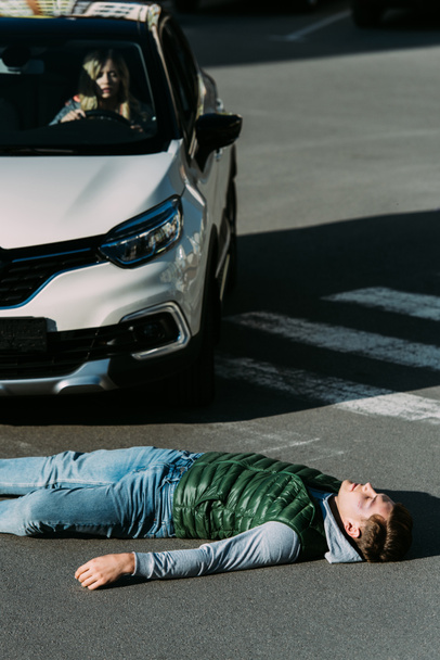 pohled z vysokého úhlu zraněného mladého muže ležícího na silnici po dopravní nehodě - Fotografie, Obrázek