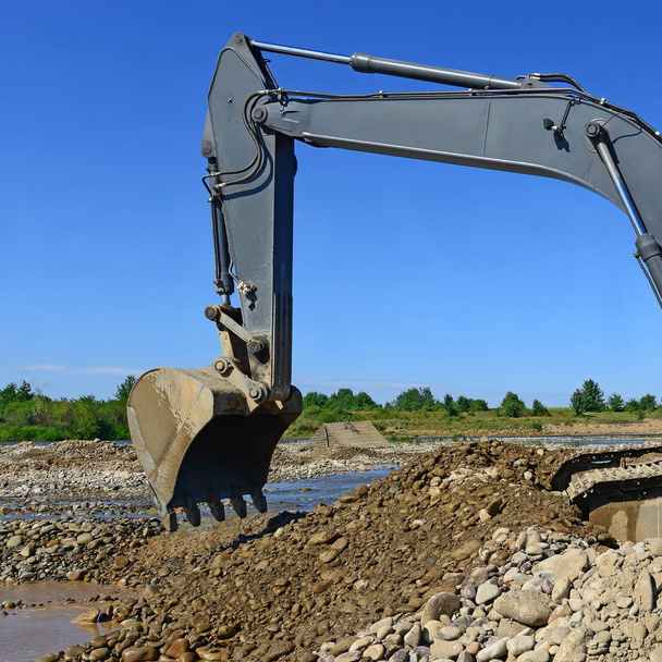Uitpakken en laden van grind opgegraven in de heersende stroming van de rivier - Foto, afbeelding
