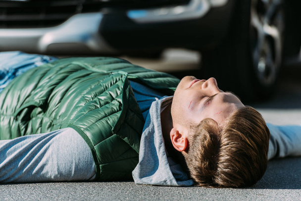 sérült fiatal férfi feküdt közúti gépjármű ütközés után kiadványról - Fotó, kép