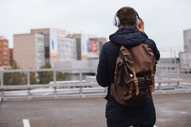 Man in headphones listening to music outdoors, back view - Foto, Imagen