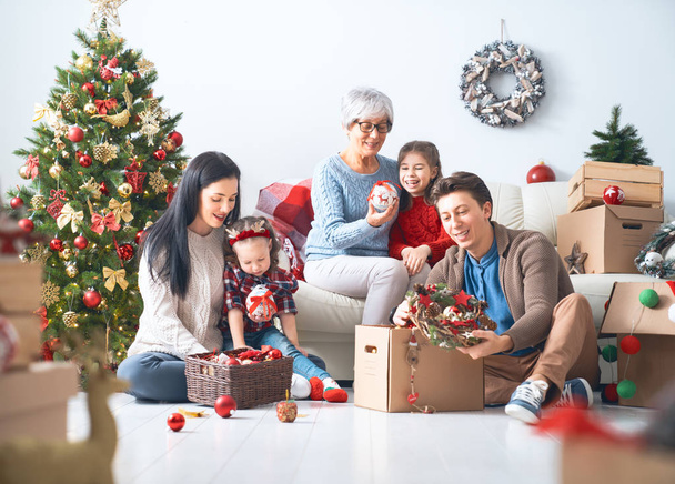 Merry Christmas and Happy Holidays!  Granny, mother, father and children decorate the tree in room. Loving family indoors. - Фото, зображення