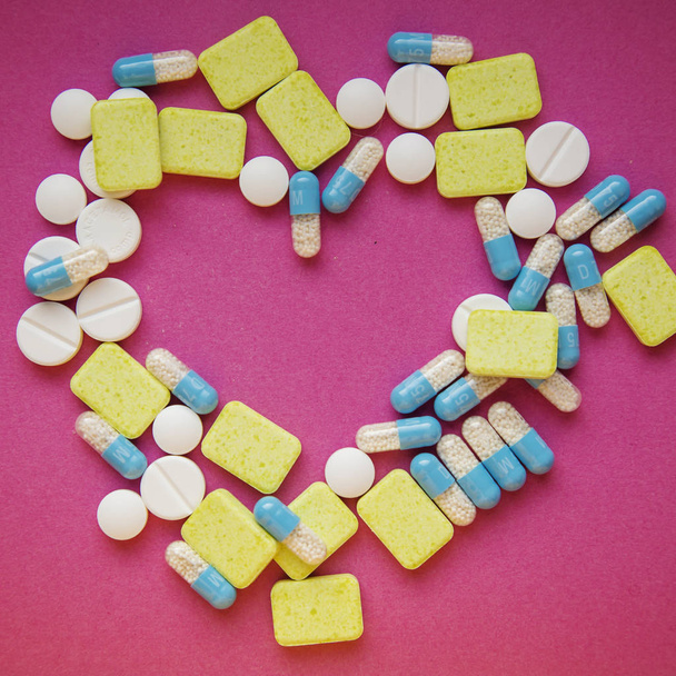 Pastillas y cápsulas farmacéuticas en el fondo en forma de corazón
  - Foto, imagen
