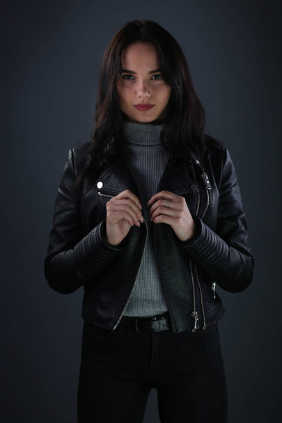 Girl in black leather jacket on dark gray background - Фото, зображення