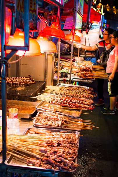 nanning, china - 9. Juni 2017: Essen auf der Zhongshan Snack Street, einem Lebensmittelmarkt in nanning mit vielen Menschen, die Lebensmittel backen und herumlaufen. diese Lebensmittelstraße ist der größte nächtliche Lebensmittelmarkt in der Hauptstadt der Provinz Guangxi in China - Foto, Bild