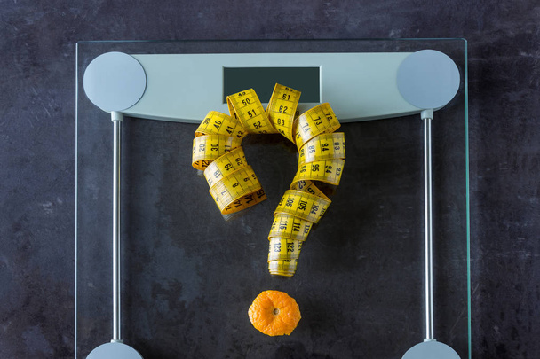 На вагах вимірюють стрічку і фруктовий апельсин. Символ знак питання. Концептуальний спосіб життя, спорт і дієта для схуднення
. - Фото, зображення