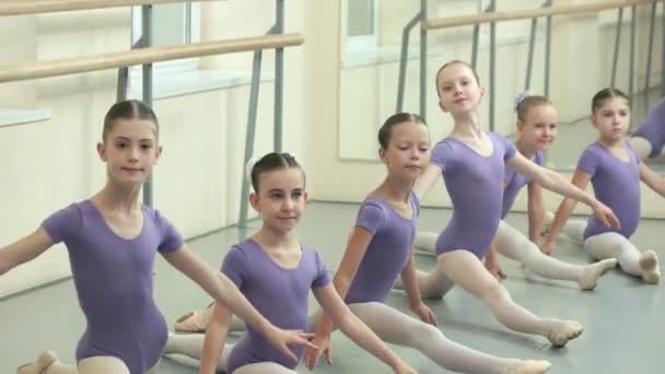 Grupa dziewcząt balet robi split w dance studio. Siedząc na podłodze na split młodej baleriny. Klasa baletu klasycznego. Marzenie z dzieciństwa. - Materiał filmowy, wideo