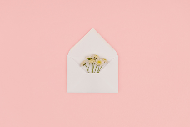 bovenaanzicht van open witte envelop met mooie bloempjes geïsoleerd op roze - Foto, afbeelding