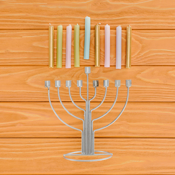 top view of traditional jewish menorah and colorful candles on wooden tabletop, hannukah holiday concept - Photo, Image