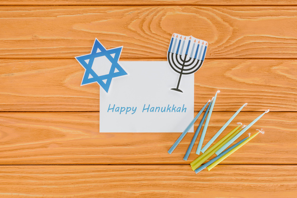 flat lay with happy hannukah card, candles and paper holiday signs on wooden tabletop, hannukah concept - Foto, afbeelding