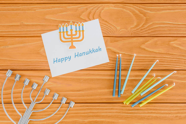 flat lay with happy hannukah card, candles and menorah on wooden surface, hannukah concept - Photo, Image
