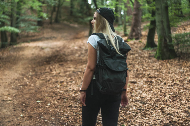 Διακινούμενη γυναίκα με σακίδιο και ΚΑΠΕΛΑΚΙ με ΓΕΙΣΟ ΣΥΣΚΕΥΑΣΙΑ. Γκντανσκ: δάσος. - Φωτογραφία, εικόνα