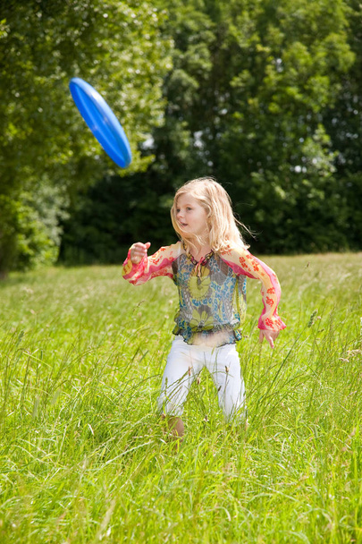 Young five year old girl throwing frisbee in the field - Fotoğraf, Görsel