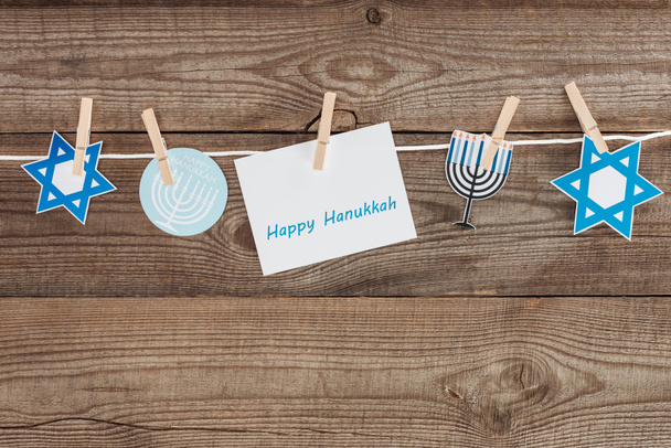 top view of happy hannukah card and holiday paper signs pegged on rope on wooden tabletop, hannukah concept - Photo, Image