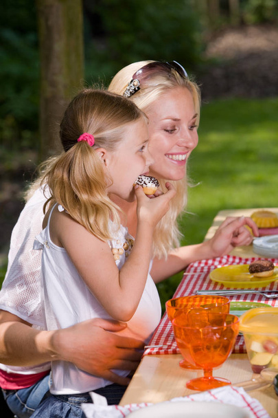 Adorable mother and daughter eating something outside on a summer's day - Foto, Imagen