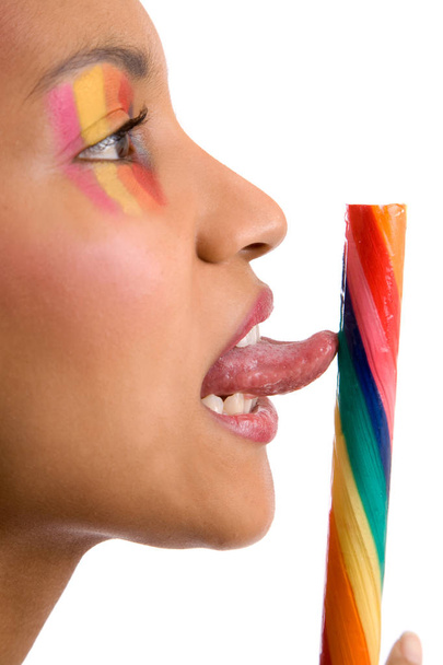 Pretty girl with colorful makeup licking a candystick (focus on tongue, shallow dof) - Фото, зображення