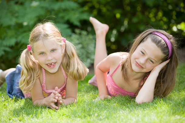 Cute young girls on a summer's day lying in the grass - Valokuva, kuva