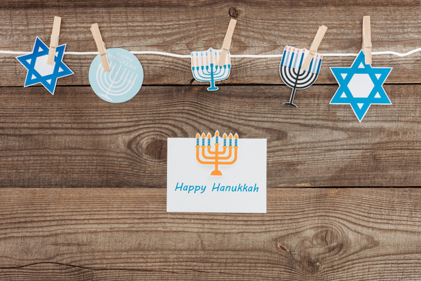flat lay with happy hannukah card and holiday paper signs pegged on rope on wooden tabletop, hannukah concept - Foto, Imagem