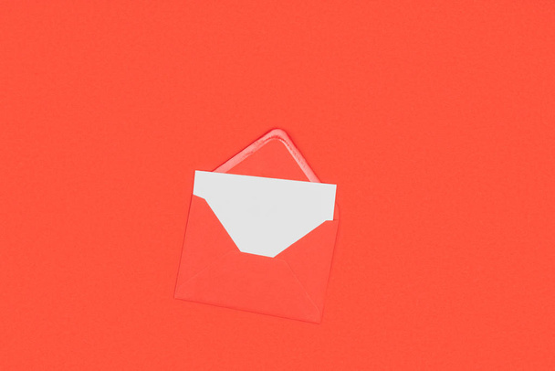 Draufsicht auf geöffneten roten Umschlag mit leerer weißer Karte isoliert auf rot - Foto, Bild