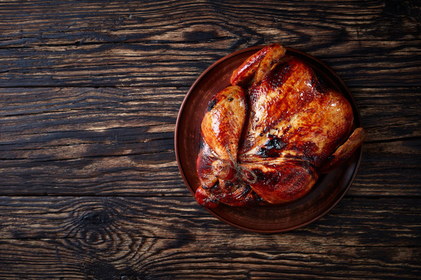 whole grilled chicken with  crispy skin on a clay plate  for Thanksgiving or Christmas Dinner, view from above, flat lay - Photo, Image