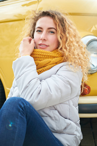 Young attractive stylish redhead curly girl siting front of yellow van and smiling. Lifestyle, travel concept.  - Zdjęcie, obraz