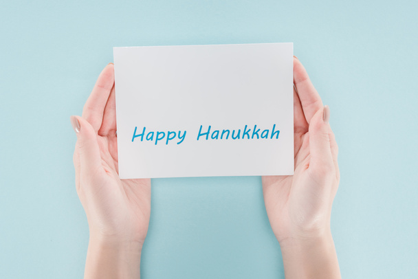 青の背景、hannukah コンセプトにハッピー hannukah の文字カードを保持している女性のクロップ撮影 - 写真・画像