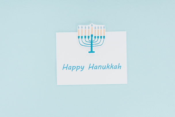 top view of happy hannukah card and paper menorah sign isolated on blue, hannukah concept - Valokuva, kuva