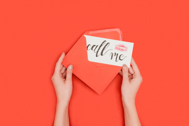 cropped shot of person holding red envelope and card with kiss mark and call me inscription isolated on red - Fotoğraf, Görsel